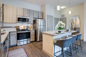 An open kitchen and dining area with stainless steel appliances and a table with chairs